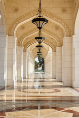 Fototapeta premium Long archway with traditional Arabian architecture leading to palm trees. Qasr Al Watan.
