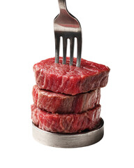 Stacked raw red meat medallions with a silver fork piercing the top cut, dark background