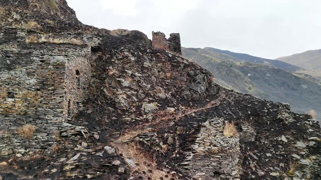 Stone medieval ruins of mutso fortress on a rocky mountain in georgia showing the defensive towers and ancient walls of the historic khevsureti village and cultural monument