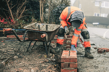 Bricklayers laying bricks building a wall building a house wearing hi vis and PPE 