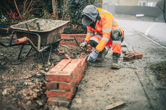 Bricklayers laying bricks building a wall building a house wearing hi vis and PPE 
