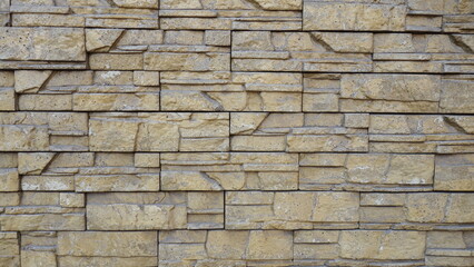 Obraz premium Textured beige stone wall with stacked pattern.