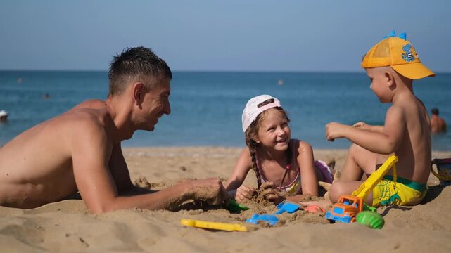 Father, son and daughter playing on the beach in the sand