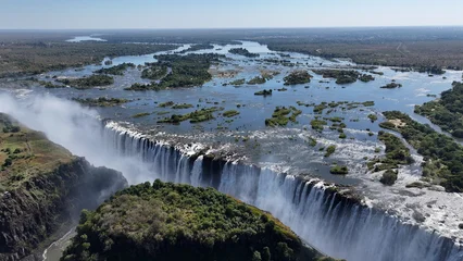 Fototapeten Wald Fluss Victoria Falls In Livingstone Northern Rhodesia Zambia. Stunning Waterfalls Flowing In Natural Wonder Landscape. Landscape Dramatic Sky Waterfall Tropical. Landscapes Waterfall Powerful Flow.  © bydronevideos