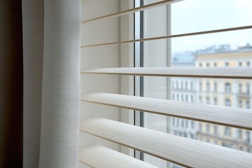 Close up of white window blinds with a blurred cityscape background