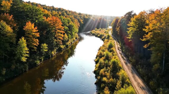 Autumnal river winds through vibrant fall foliage and a winding roadway