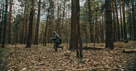 Obraz premium German soldier running with rifle through forest during WWII reenactment