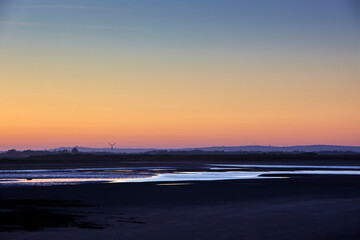 Obraz premium Serene beach landscape at dusk with warm orange and blue gradient sky in soft focus for travel background