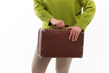 A young slender girl in a bright sweater is preparing for a trip to another country or moving to another city for training or internship. A woman packs a vintage suitcase for the road