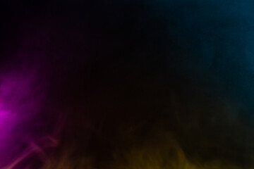 Layered colorful smoke moving on a dark background, creating an abstract and dynamic display of blue, yellow, and magenta