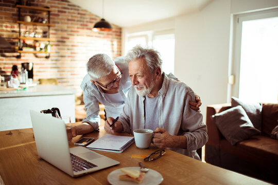 Smiling senior couple budgeting at kitchen table