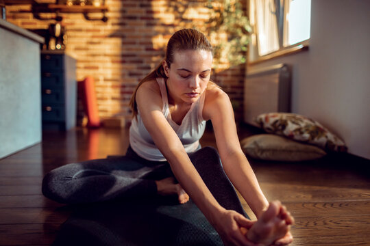 Young woman stretching on yoga mat at home