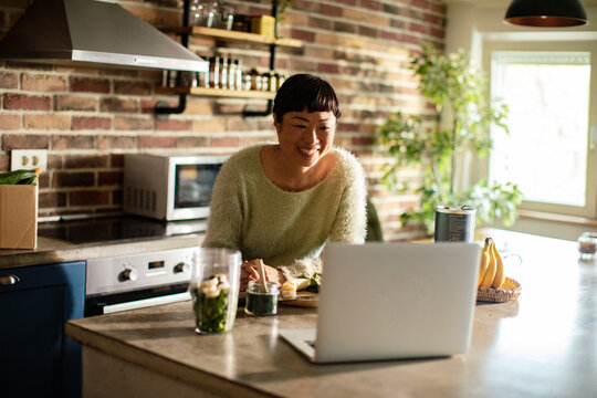 Smiling woman following an online cooking class in a home kitchen