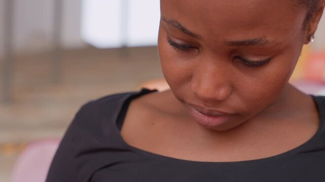 young black woman looking down reading with concentrated expression, closeup on chest and hands, bleacher background, intimate study moment showing focus, quiet mood and natural skin detail