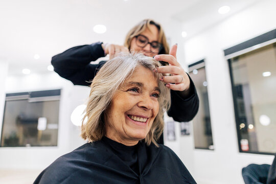 Senior woman smiling while getting a haircut