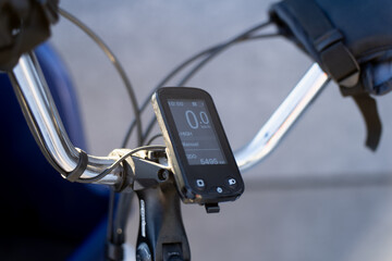 Digital bike computer display on bicycle handlebar with cables and mount, closeup of modern cycling technology for commuting, training and navigation use