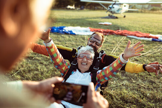Happy senior woman tandem skydiving landing at airfield