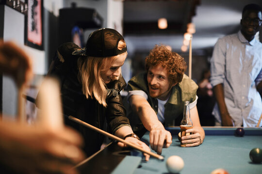 Young friends playing pool at a bar
