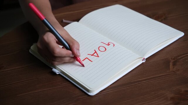 a hand writing on Blank notebook page with the word goals in bold red marker on white background, perfect for setting personal objectives and planning future projects or aspirations