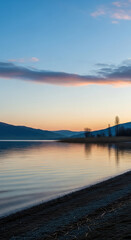 Obraz premium Serene lake at dusk with colorful clouds reflecting on calm water surface