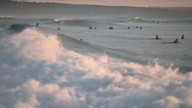 Wide ocean view with surfers and rolling sets