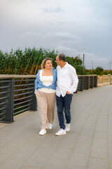 A middle-aged couple, husband and wife, enjoy each other's company during a walk in the park.