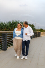 A middle-aged couple, husband and wife, enjoy each other's company during a walk in the park.