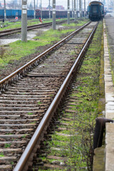Fototapeta premium the texture of wooden railway sleepers and steel rails stretching into the distance toward a blurred train car.