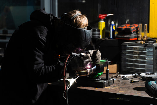 TIG Tungsten Inert Gas welding of custom car exhaust muffler in automotive workshop