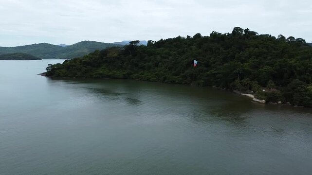 Tandem paramotor flying in Brazil over the water with a stunning view of the Paraty Bay, the small islands and the mountains covered with dense forest in Paraty