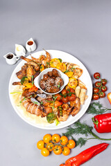 Top view of chicken platter with vegetables cheese and sauce on grey background