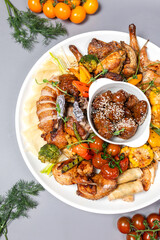 Top view of chicken platter with vegetables and sauce on white plate