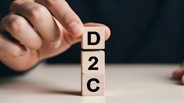 Hand arranging wooden blocks with d2c spelling in a dark office workspace