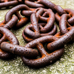 Fototapeta premium Rusty metal chain on a concrete surface with visible rust and corrosion, captured from a close-up viewpoint