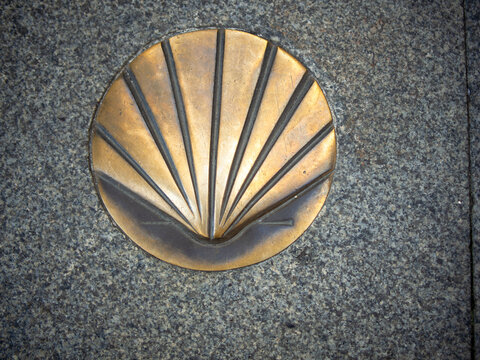 Close-up of a Camino de Santiago scallop shell marker on a stone street