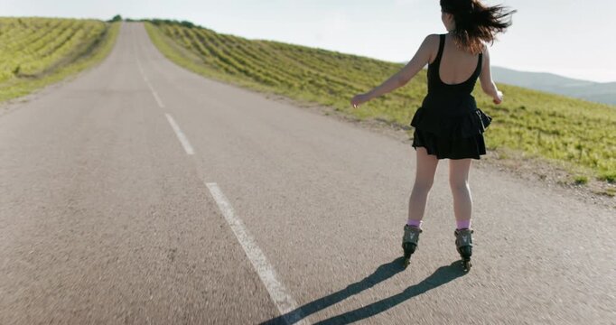 Young woman in black dress riding and training on roller blading