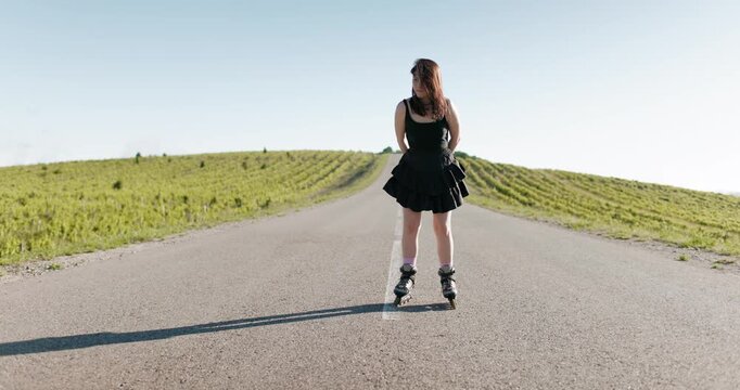 Young woman in black dress training on roller blading