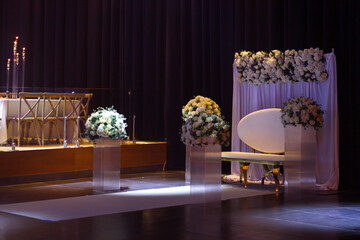Elegant ceremony hall decoration with a bridal throne adorned with flowers.