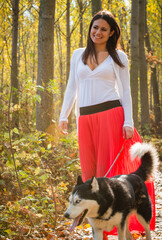 Obraz premium The girl is walking along the forest with her husky dog