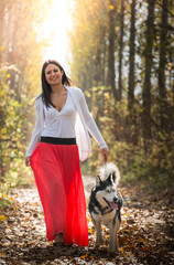 Obraz premium The girl is walking along the forest with her husky dog