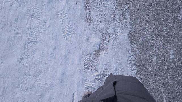 A person walks along a snowy path leaving footprints in the fresh snow.