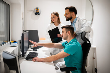 Medical team collaborating on computer in clinic office