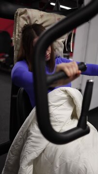 Vertical screen the girl half asleep keeps holding the gym machine as the girl tries to train even while drifting off showing how strong her commitment is to stay active no matter how tired