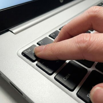 Close up of finger pressing escape key on laptop