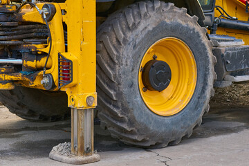 Fototapeta premium Lifting machine truck crane stands on stops,large wheel of tractor