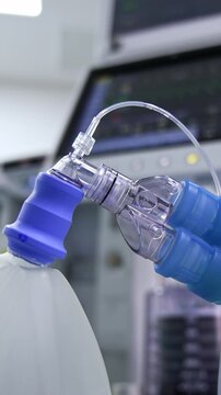 The ambu bag with two thick tubes connected. Close up. Lung ventilation machine at backdrop in blur. Vertical video