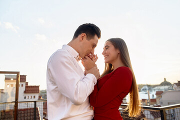 Fototapeta premium Couple shares a moment on rooftop during sunset overlooking the city skyline