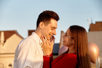 Naklejka premium Couple enjoys a moment together in the sunlight on a rooftop during a warm evening