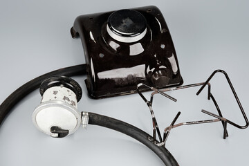 A dark portable gas stove burner, a silver gas regulator with a black hose, and a metal pot support rest on a grey background