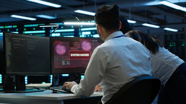 Cybersecurity analysts in a security operations center responding to critical malware alerts on multiple screens, investigating threats in real time

